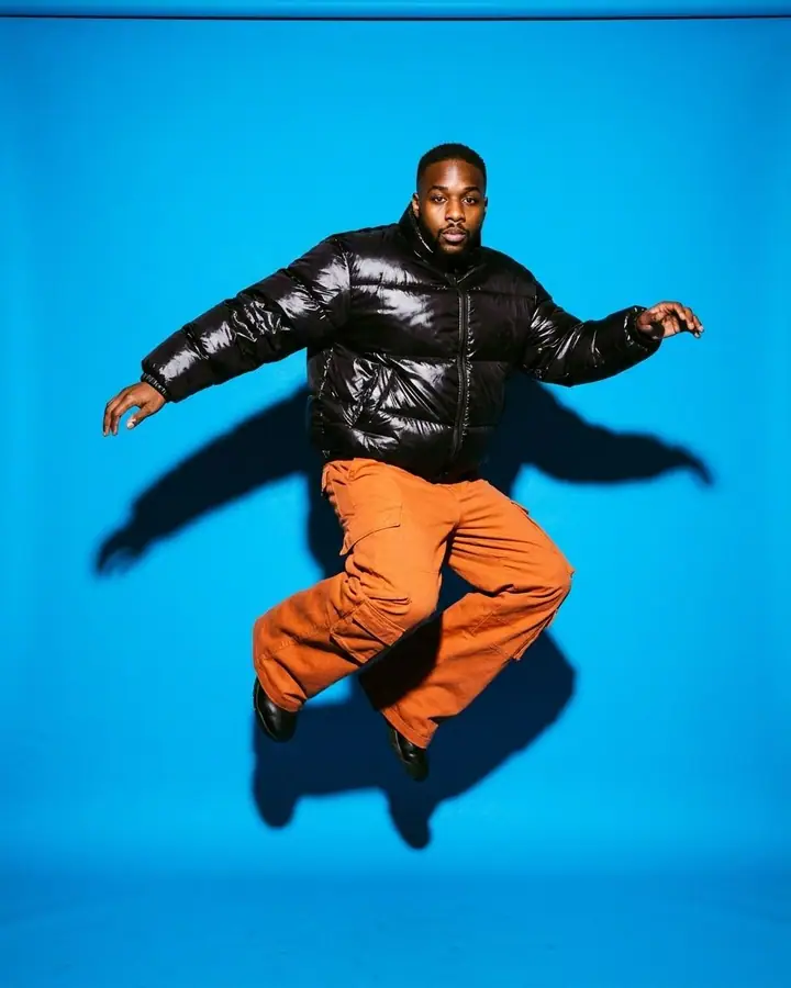 AI example of a man jumping in a puffer jacket against an electric blue backdrop