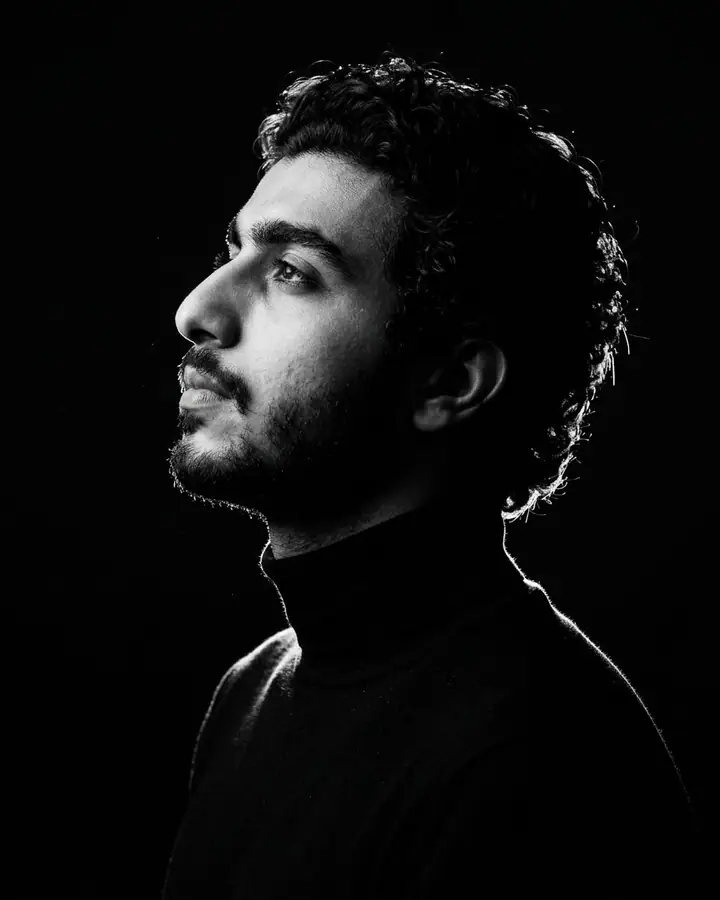 Black and white side profile lit only by a hard rim light on a black background