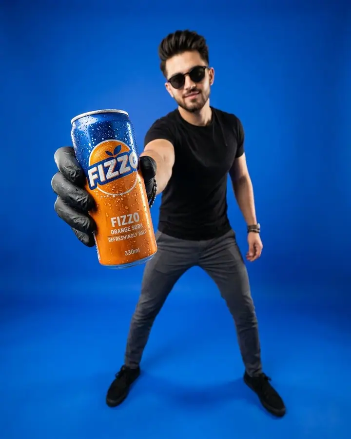 Man on a blue studio set holding a drink can very close to the camera