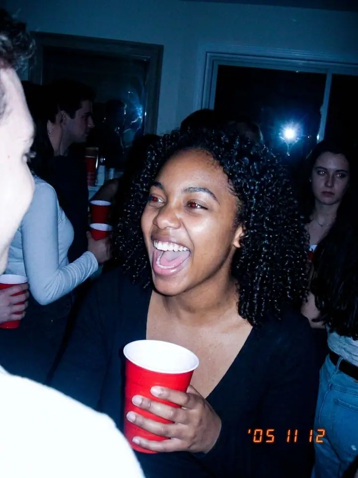 AI example of a 2000s point-and-shoot flash party photo of a woman laughing